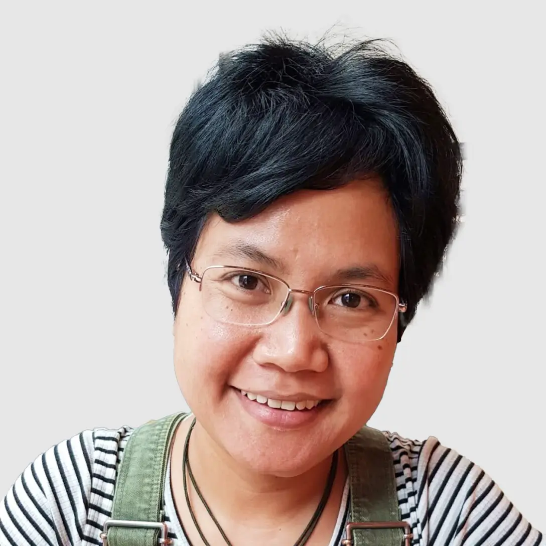 Portrait of a woman teacher with medium-length dark hair, looking confident and approachable, with a solid soft colored background